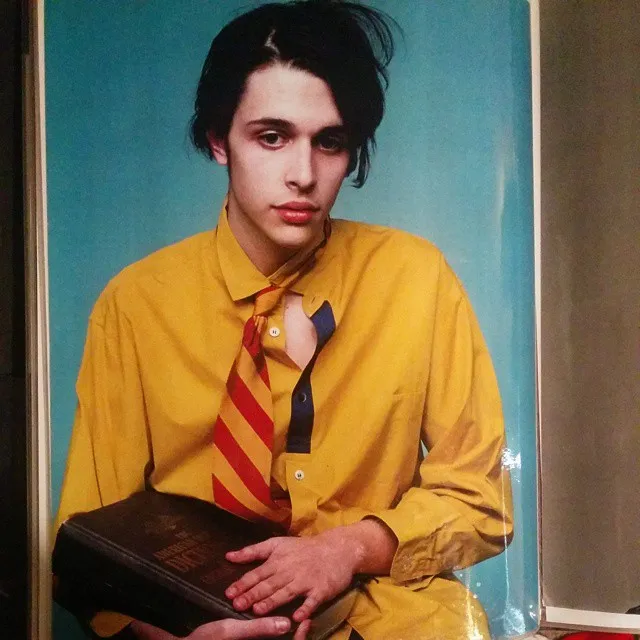 Modeling shot of Jake in a yellow shirt and striped tie, holding a dictionary
