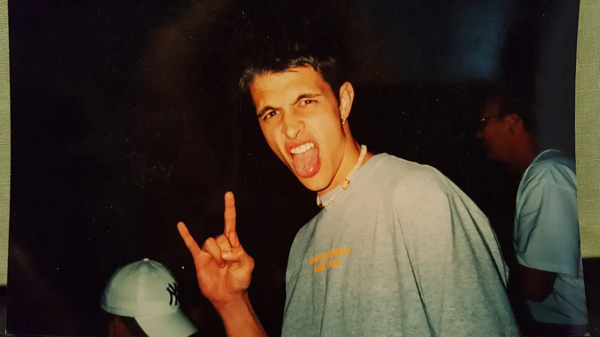Jake at a party, tongue out, throwing the horns